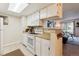 Bright kitchen featuring white appliances, breakfast bar, and an inviting view into the living room at 8555 Fairmount Dr # B202, Denver, CO 80247