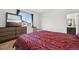 Bright bedroom with a large window, modern dresser, and a red and black patterned comforter at 5278 Warrior St, Frederick, CO 80504
