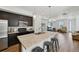 Modern kitchen with stainless steel appliances, a center island with seating, and an open view to the living area at 5278 Warrior St, Frederick, CO 80504