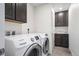 This laundry room has a modern washer and dryer, dark cabinets, tile floors, and a sink at 14119 Glencoe St, Thornton, CO 80602