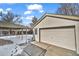 Attached garage with a carport and concrete driveway surrounded by snow at 6631 E 77Th Pl, Commerce City, CO 80022