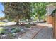 Landscaped front yard with decorative features, mature trees, and a charming walkway at 2117 S Balsam Ct, Lakewood, CO 80227