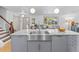 Bright kitchen featuring a stainless steel farmhouse sink and granite countertops with seamless transition into living space at 2117 S Balsam Ct, Lakewood, CO 80227