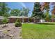 Backyard view of brick home with mature trees and a large green lawn at 3784 Swadley St, Wheat Ridge, CO 80033