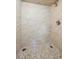 A well-lit shower featuring neutral stone-look tiling and pebble stone floor at 3784 Swadley St, Wheat Ridge, CO 80033