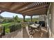 A partially covered deck boasts outdoor dining with stunning views of a green lawn and lush landscape at 17490 W 67Th Ave, Arvada, CO 80007