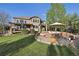 Large backyard with manicured lawn, mature trees, deck, stone patio and outdoor furniture at 17490 W 67Th Ave, Arvada, CO 80007