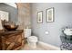 Powder room featuring a wooden vanity, bronze vessel sink, and decorative tile accent wall at 17490 W 67Th Ave, Arvada, CO 80007