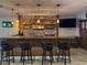 Finished basement bar featuring brick accents, wood shelves and an island with seating at 5893 Lasso Pl, Parker, CO 80134