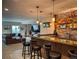 Finished basement bar featuring brick accents, wood shelves, an island with seating and an adjacent sitting area at 5893 Lasso Pl, Parker, CO 80134