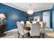 Dining room featuring a blue accent wall, modern chandelier, and seating for six around a round table at 7963 S Valleyhead Way, Aurora, CO 80016