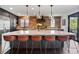 Modern kitchen boasts a marble island with barstool seating, brick backsplash, and pendant lighting at 7963 S Valleyhead Way, Aurora, CO 80016