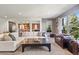 Open concept living room featuring a large sectional sofa, exposed brick in the kitchen and natural light from large windows at 7963 S Valleyhead Way, Aurora, CO 80016