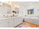 Bright bathroom featuring double vanity, gold fixtures, and a soaking tub with a scenic outdoor view at 5090 S Perry Park, Sedalia, CO 80135