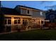 Back of house at dusk features outdoor lighting, wooden deck and grassy yard at 16177 E Prentice Pl, Centennial, CO 80015