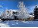 Charming two-story brick home covered in fresh snow with snow-covered trees in the front yard at 16177 E Prentice Pl, Centennial, CO 80015
