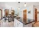 Open kitchen with granite island, white cabinetry, and dining area with brick fireplace at 16177 E Prentice Pl, Centennial, CO 80015