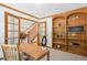 Well-lit home office with wooden desk, built-in bookshelves, and glass doors offering a quiet workspace at 16177 E Prentice Pl, Centennial, CO 80015