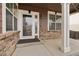 Charming front porch featuring brick accents, white pillars, and a welcoming entryway with a storm door at 6373 E 130Th Ave, Thornton, CO 80602