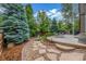 Landscaped backyard with a stone patio, lush greenery, and a charming rock garden at 14258 Greenfield Loop, Parker, CO 80134