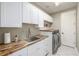 Modern laundry room with butcher block countertops, white cabinetry, and stainless steel washer and dryer at 14258 Greenfield Loop, Parker, CO 80134