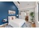 Stylish bedroom with blue accent wall, modern decor, and sliding barn door to en-suite bathroom at 4590 Wolff St, Denver, CO 80212