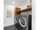 Well-equipped laundry room featuring gray front-loading machines, modern cabinets, and decorative art at 4590 Wolff St, Denver, CO 80212