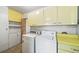 Functional laundry room featuring washer, dryer, storage cabinets, and yellow vintage accents at 2571 S Birch St, Denver, CO 80222