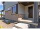 Close-up of a home's entry showing brick foundation and covered porch with a dark front door and concrete steps at 1443 Great Western Dr, Longmont, CO 80501