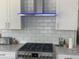 Modern kitchen featuring a stainless steel range hood over a gas cooktop with subway tile backsplash at 15498 E Dorado Pl, Centennial, CO 80015