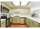 Well-lit kitchen with stainless steel appliances, light green cabinets, and a view into the cozy living area at 8422 Everett Way # C, Arvada, CO 80005