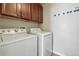 Bright laundry room featuring a washer and dryer with overhead cabinets and convenient hanging rack at 31112 Black Eagle Dr # 103, Evergreen, CO 80439