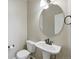Classic powder room with pedestal sink, circular mirror, and modern fixtures at 31112 Black Eagle Dr # 103, Evergreen, CO 80439