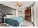 Comfortable bedroom with a patterned accent wall, cozy bed, and dark wood armoire for ample storage at 3798 E 118Th Way, Thornton, CO 80233