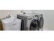 A laundry room featuring a deep utility sink next to a modern silver washer and dryer set at 6483 S Irvington Way, Aurora, CO 80016