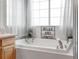 Bathroom featuring a soaking tub with a window, and a relaxing sign at 2414 Winding Dr, Longmont, CO 80504