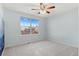 Bright bedroom with neutral carpet, ceiling fan, and a large window at 2414 Winding Dr, Longmont, CO 80504