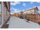 Backyard with snow offers potential for outdoor activities, with a wood fence and adjacent houses creating privacy at 25127 E Maple Ave, Aurora, CO 80018
