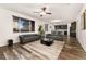Open-concept living room and kitchen area with hardwood floors, ceiling fan, and comfortable gray sofas at 25127 E Maple Ave, Aurora, CO 80018