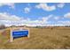 A sign at Traditions Park surrounded by open green space. Ideal location with plenty of room for recreational activities at 25127 E Maple Ave, Aurora, CO 80018