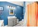 This well lit bathroom features a gray vanity and sink with a decorative mirror and brightly colored shower curtain at 26351 Sheldon St, Kittredge, CO 80457