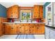 A charming kitchen with wooden cabinets, a window with plants, and blue walls at 26351 Sheldon St, Kittredge, CO 80457