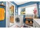 This laundry room has tile floors, white walls and a washer and dryer, along with a bright window and blue walls at 26351 Sheldon St, Kittredge, CO 80457