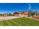 A charming exterior view showcasing well-manicured landscaping, a brick and red home, and a driveway at 15373 Uravan St, Brighton, CO 80601