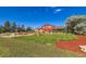 Lush exterior view of a home with well-maintained landscaping, a vibrant red home, and a sprawling yard at 15373 Uravan St, Brighton, CO 80601