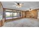Living room with wood paneled walls, large windows, ceiling fans, and access to patio at 4095 Field Dr, Wheat Ridge, CO 80033
