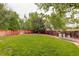 Large fenced backyard with a well-maintained lawn and mature trees at 10364 Ravenswood Way, Highlands Ranch, CO 80130