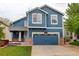 Charming two-story home featuring a blue exterior, landscaped yard, and a two-car garage at 10364 Ravenswood Way, Highlands Ranch, CO 80130