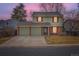 Charming two-story home with red shutters, a well-kept lawn, and a convenient two-car garage at dusk at 8155 Everett E St, Arvada, CO 80005