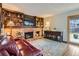 Comfortable living room featuring a brick fireplace with built-in shelving, a red leather couch, and a rug at 8155 Everett E St, Arvada, CO 80005